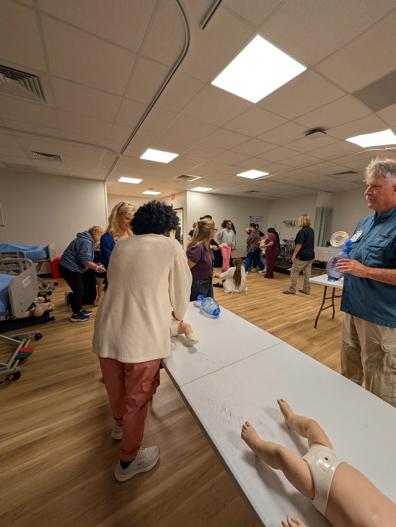 Student performing CPR on a baby doll