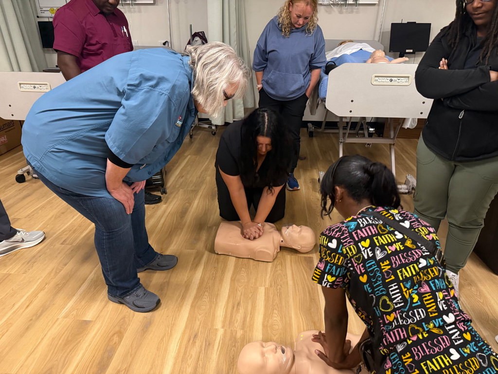 Students performing CPR on multiple mannequins while instructor watches