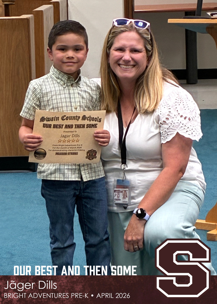 A young boy holds a Swain County Schools certificate while posing with a smiling woman wearing a white blouse and sunglasses on her head.