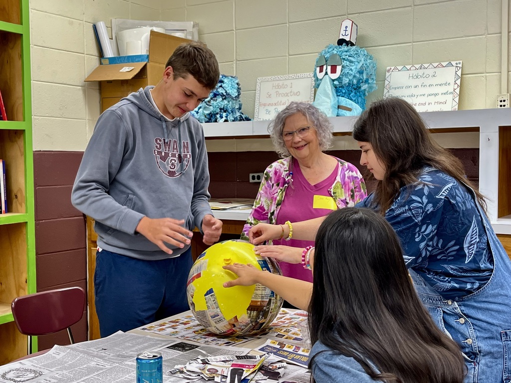 Students and teachers working on paper mache ball