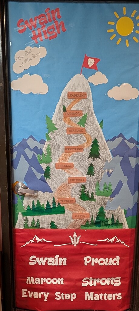 Picture of a Homecoming Week Door Design. A mountain with all the character traits listed kindness, persevernce, integrity which you climb to become a Maroon Strong person of character