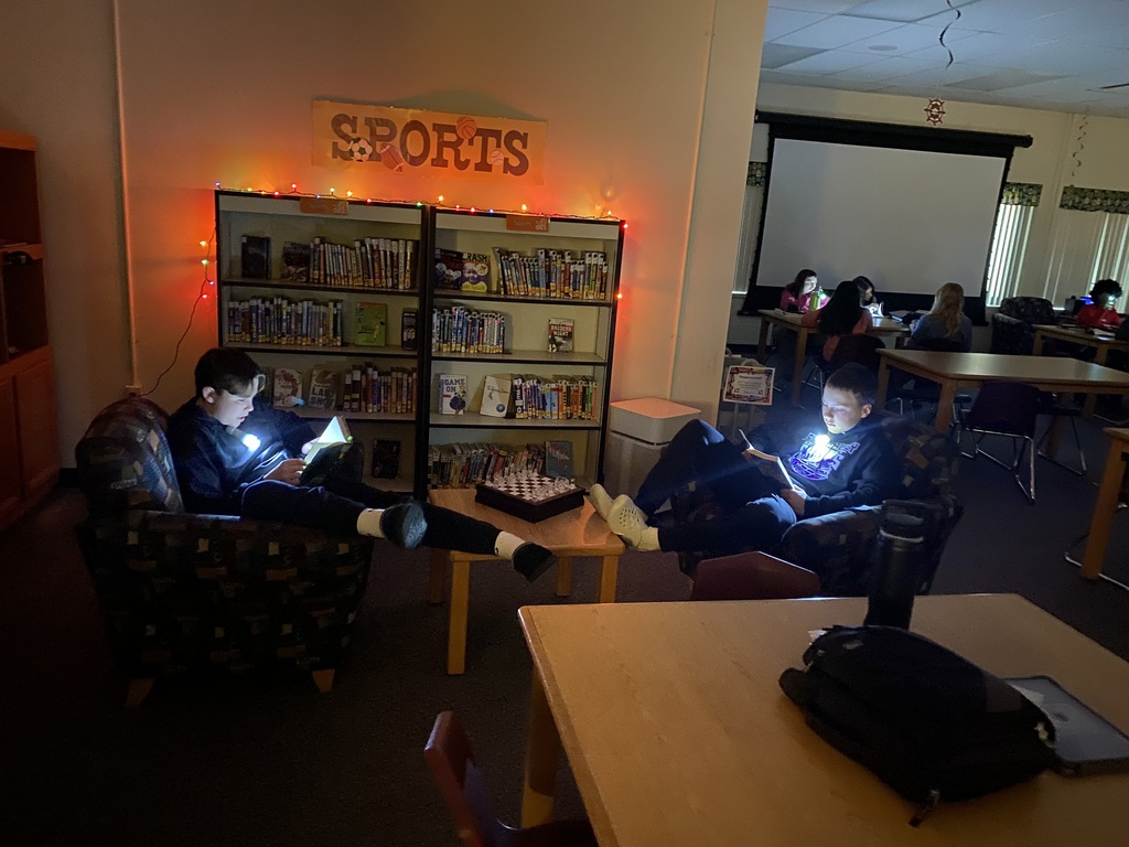 Students reading books using flashlights.
