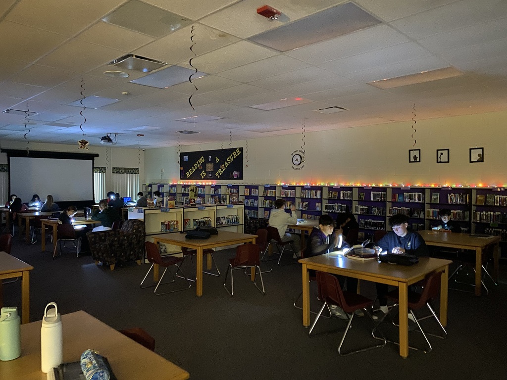 Students reading books using flashlights.