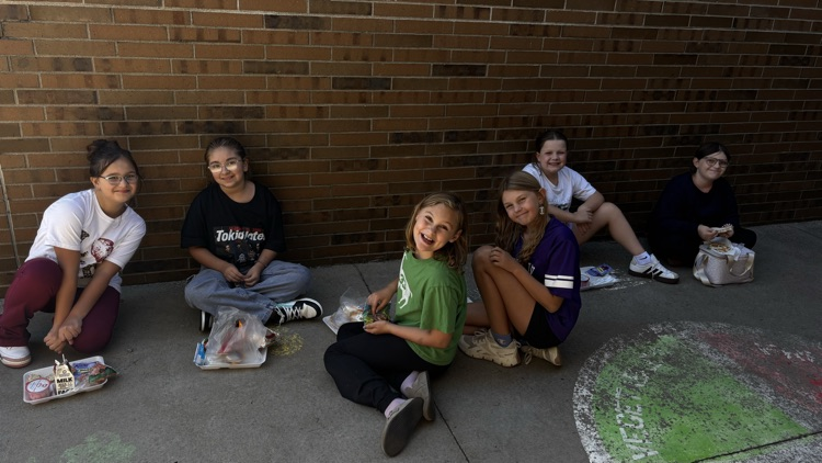 A bunch of fourth grade Vikings are eating lunch outside while enjoying the sunshine.