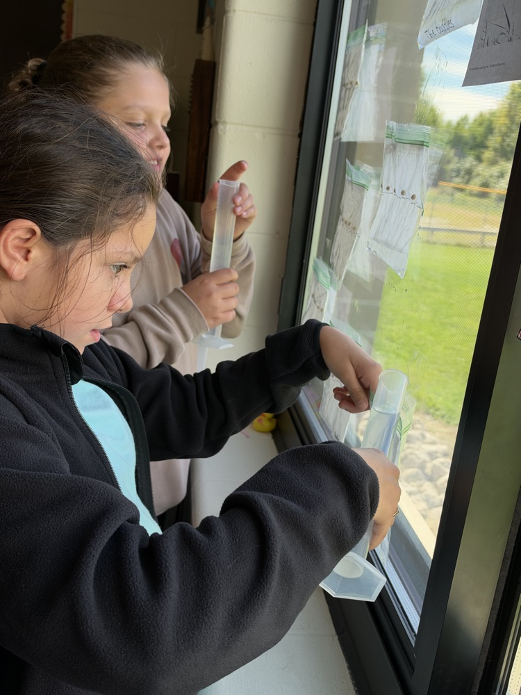 Two fifth grade student get ready to hang their bags on the window.