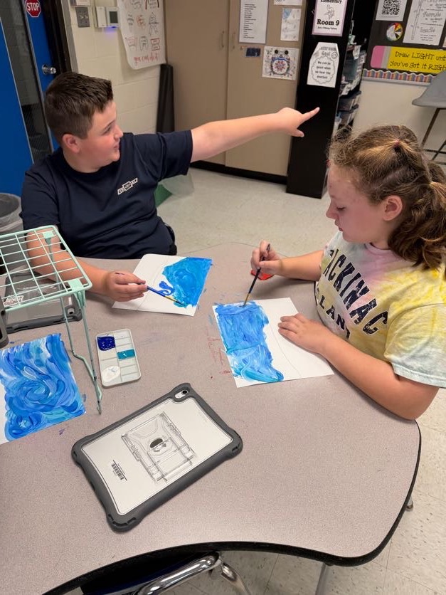 students panting blue swirls, one student points to something off to side