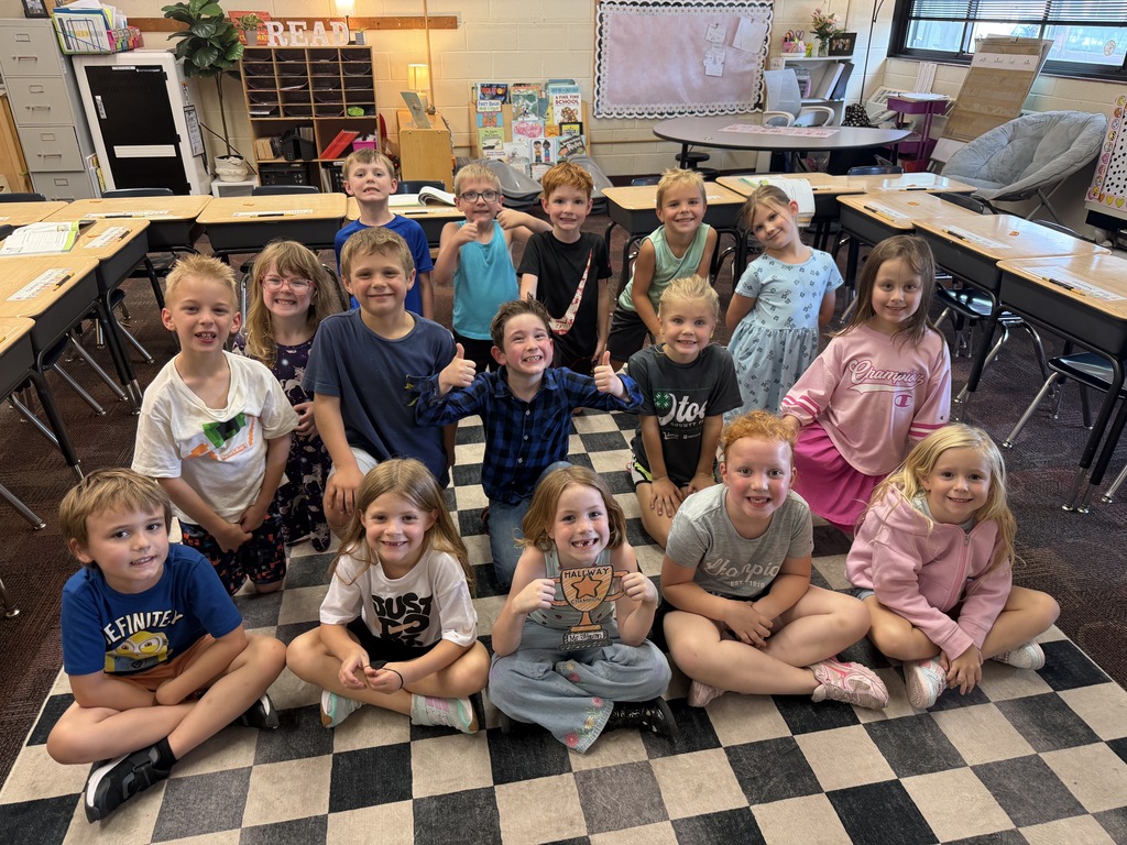class sitting on floor with trophy