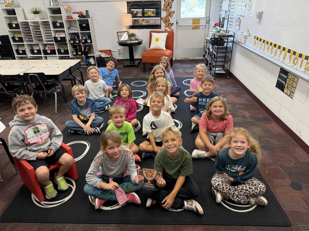 1st grade class sitting on carpet with trophy