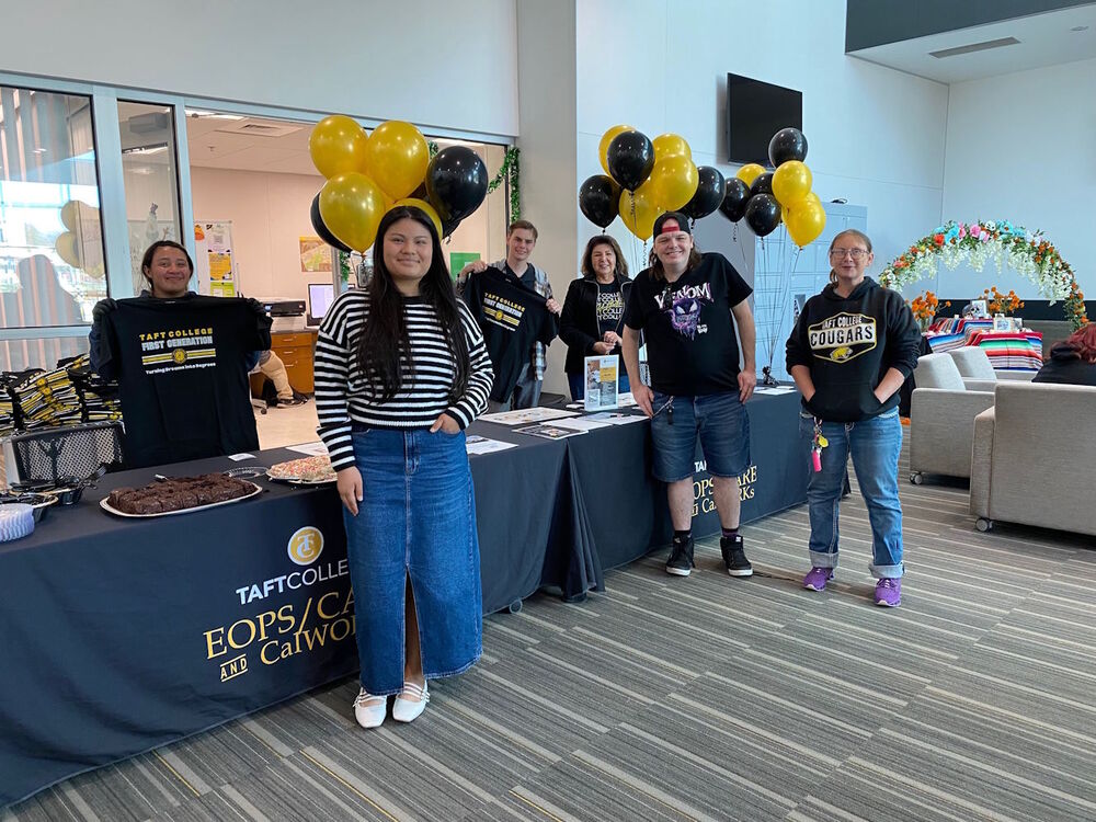 Students and Staff standing in front of a table at an EOPS/CARE event.