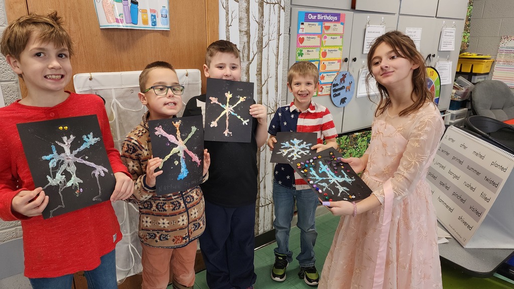 Students holding snowflake paintings