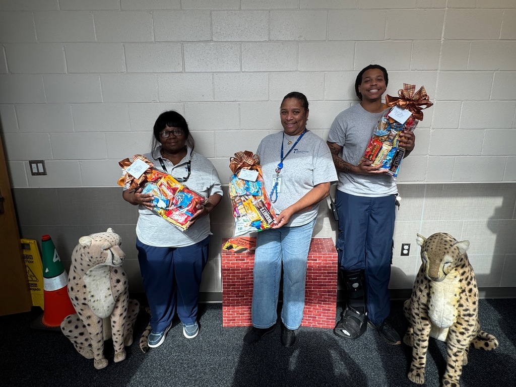 Two African American female and one African American Male custodian with gift baskets.