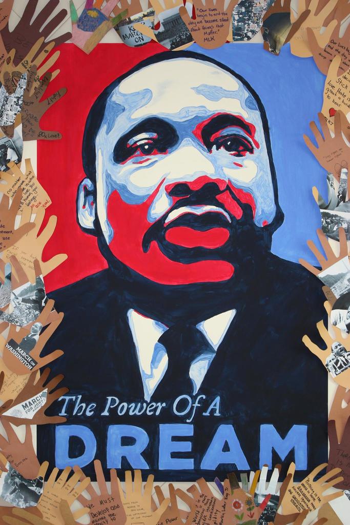 a painting of MLK Jr. in patriotic colors surrounded by paper cut-out hands with messages of encouragement, peace, and reflection inspired by Dr. King’s legacy