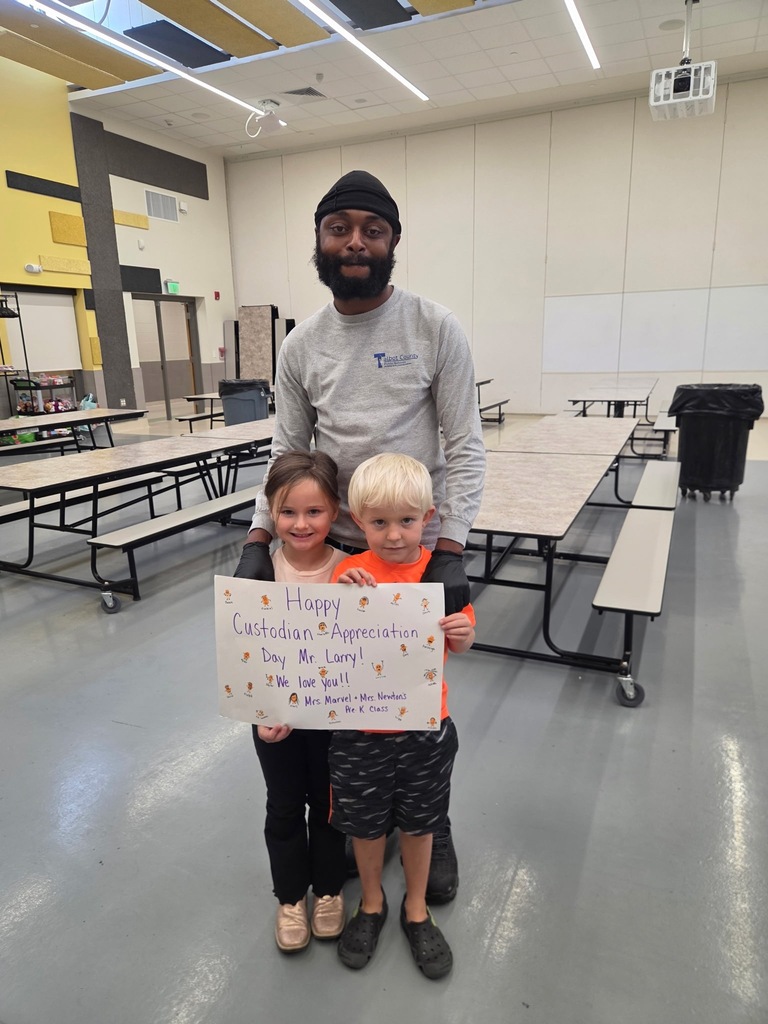 Custodian posing with students and a sign that says "Happy Custodian Appreciation Day Mr. Larry!"