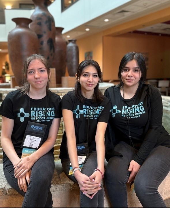 three students on a bench, wearing t-shirts for the educators rising conference