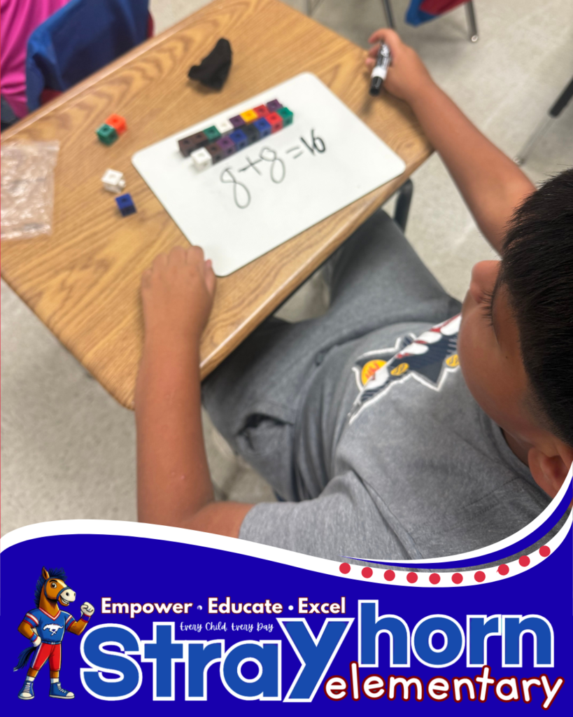 student with cubes and marker writing addition facts on whiteboard at desk