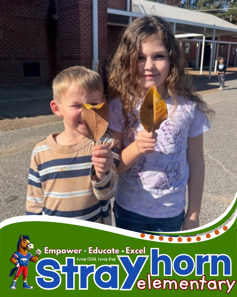 2 students holding up leafs smiling at camera