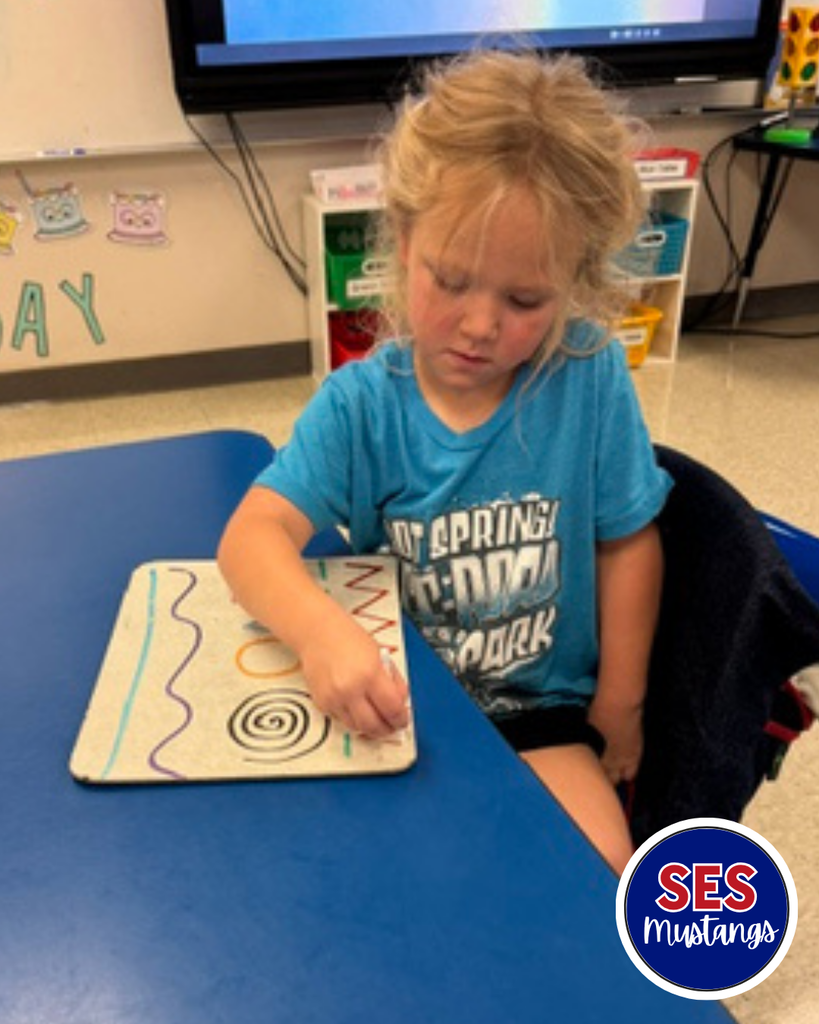 Child with q-tip erasing lines on a whiteboard.