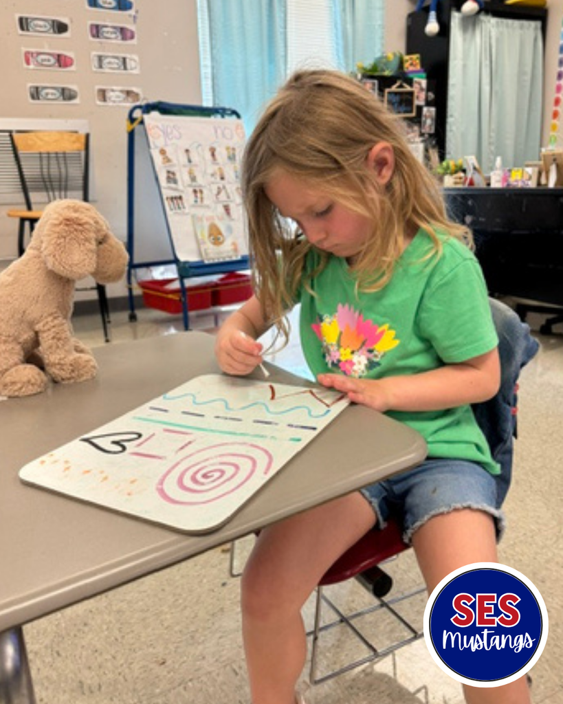 Child with q-tip erasing lines on a whiteboard.