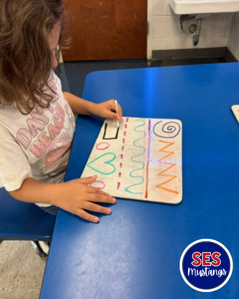 Child with q-tip erasing lines on a whiteboard.