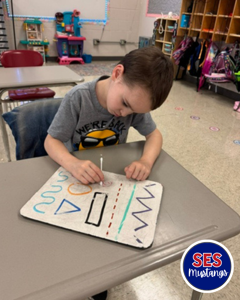 Child with q-tip erasing lines on a whiteboard.