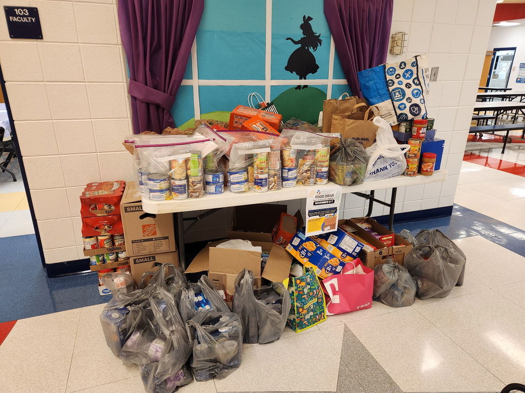 boxes and bags of food on and under a table that will be donated