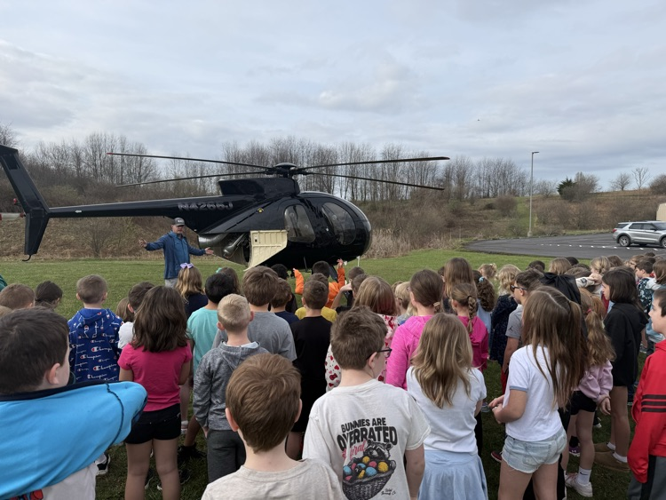 Pre-K through first grade students listening to Justin Prickett show his helicopter 