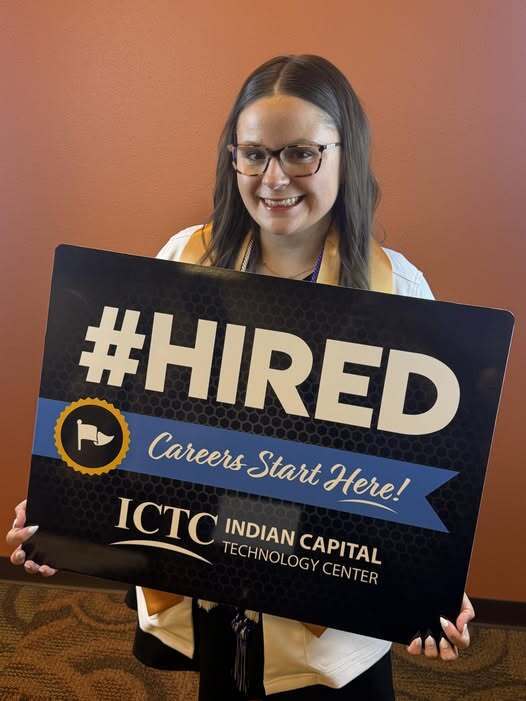 Woman holding a sign that reads "#HIRED Careers Start Here!" with a blue ribbon and logo for ICTC Indian Capital Technology Center.