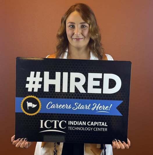 A woman holding a black sign with the hashtag #HIRED and "Careers Start Here!" in white.