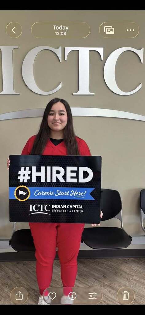 Person holding sign that reads "#HIRED Careers Start Here!" in front of ICTC logo on wall.