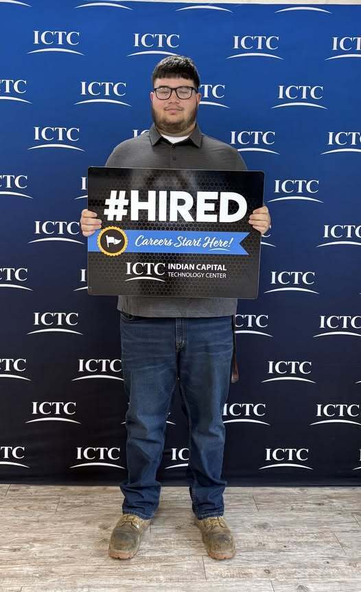 Person standing, holding a sign that says "#HIRED" and "Careers Start Here!" with an Indian Capital Technology Center backdrop.