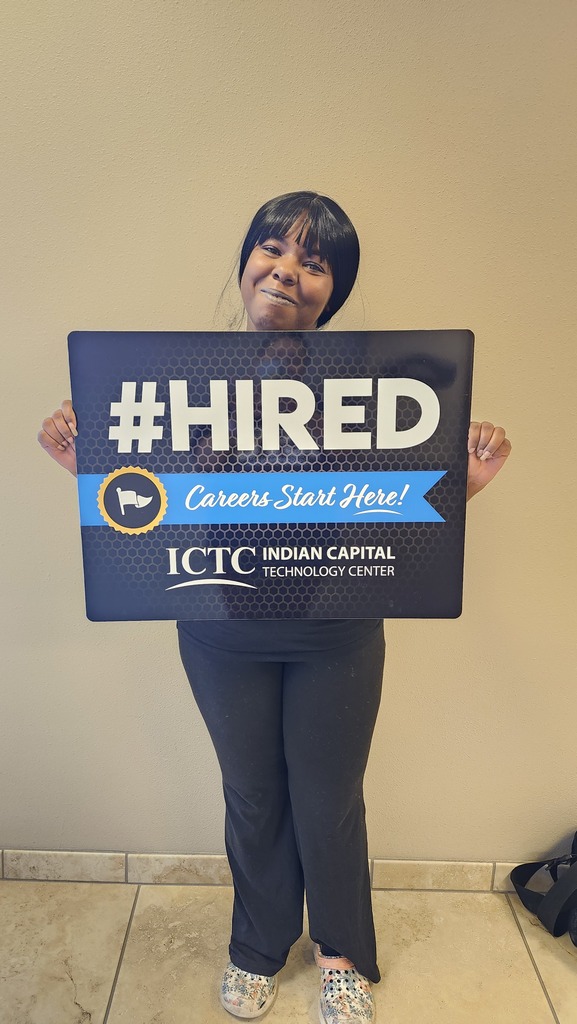 Person holding a blue sign with white letters that reads "#HIRED Careers Start Here!" against a beige background.