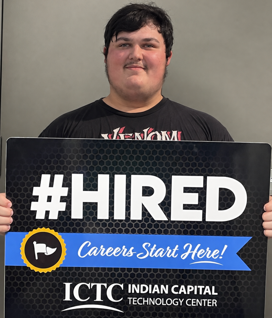 Person in black t-shirt holds a sign reading "#HIRED Careers Start Here!" with a blue ribbon and ICTC logo.