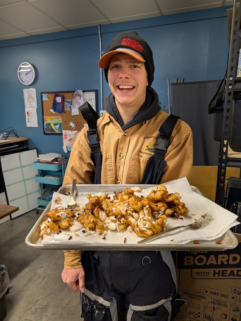 Student holds a tray of deep fried fish they cooked