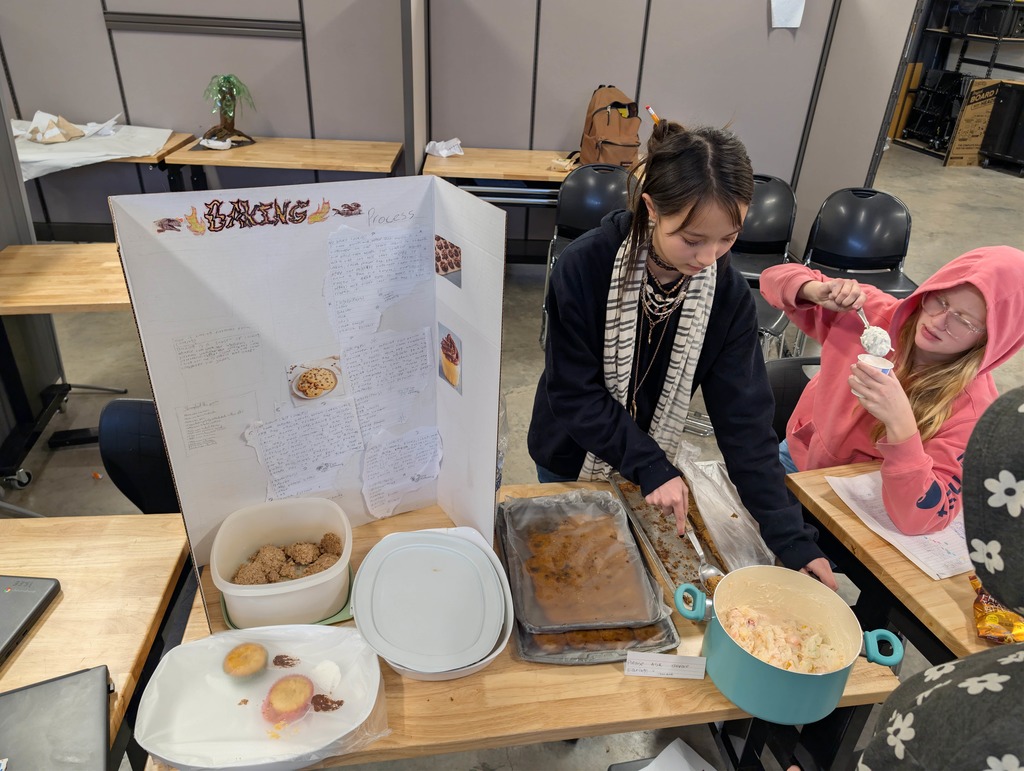 Student displays poster board about cooking and serves baked goods 
