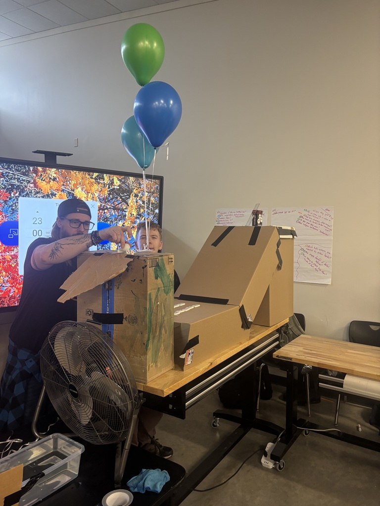student set up cardboard boxes and balloons for experiment 