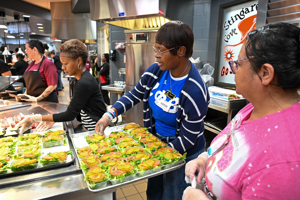 A Leaders of Impact participant helps serve lunch alongside a Nutrition Services staff member at Texas City High School.