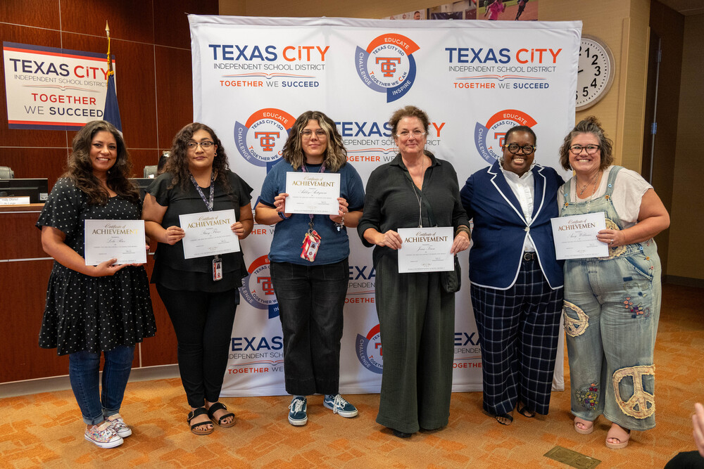 Group of art teachers pose with their recognition certificates and the school board president