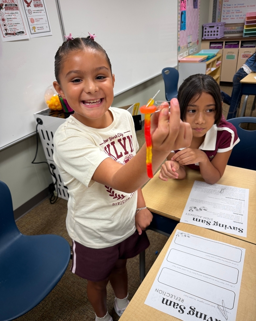 A student smiles while showing the result of the Saving Sam activity.