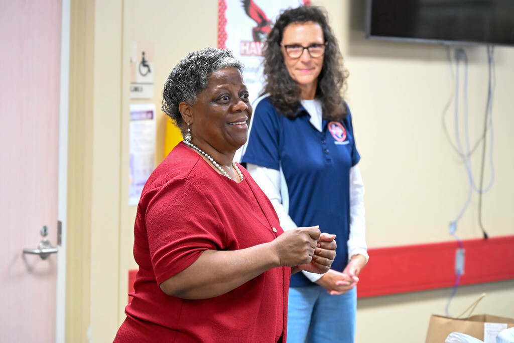 A district leader smiles while addressing Heights Elementary staff during the recognition announcement.