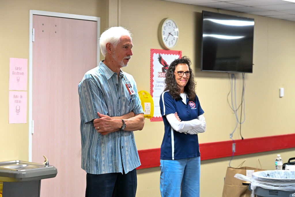 Two education leaders stand before Heights Elementary staff during the announcement of the school’s statewide recognition.