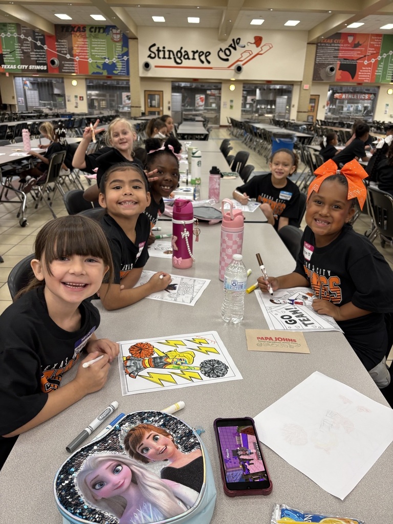 Young cheer clinic participants smile while coloring together in the TCHS cafeteria