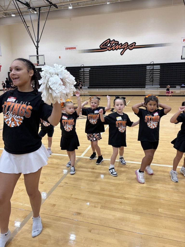 A TCHS cheerleader leads a group of young participants through a cheer in the gym.