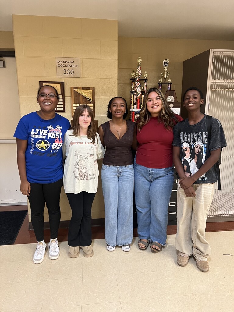 Five choir students pose together smiling.