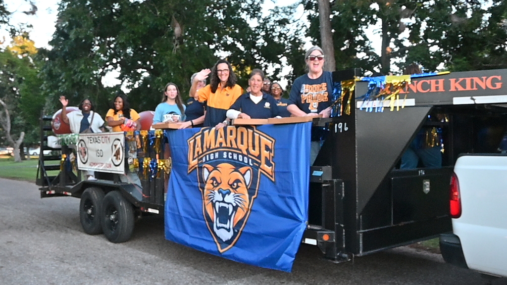 The TCISD superintendent, administrators and school board members wave and throw candy from a float with a La Marque Cougar flag on the side of the trailer.