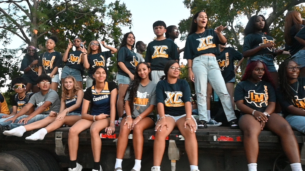 Members of the cross country and volleyball teams ride on a float