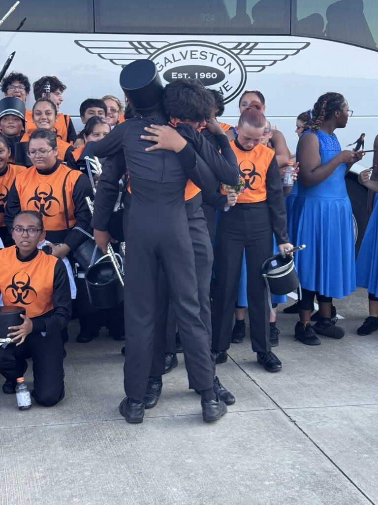 Two band students embrace after earning Superior ratings at marching contest.
