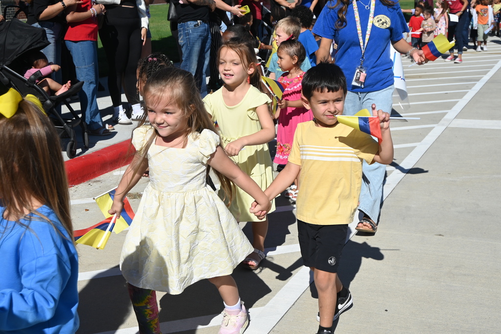 Students dressed in yellow, blue and red carrying the yellow, blue and red flag of Columbia.