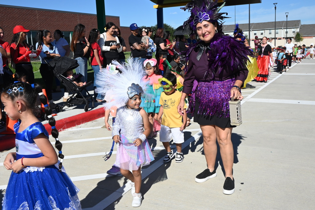 A student and teacher wear traditional headgear with lots of feathers and also wear sparkly skirts and tops to represent traditional Carnival type of dress for Brazil. Other students dress like birds that are popular in Brazil.