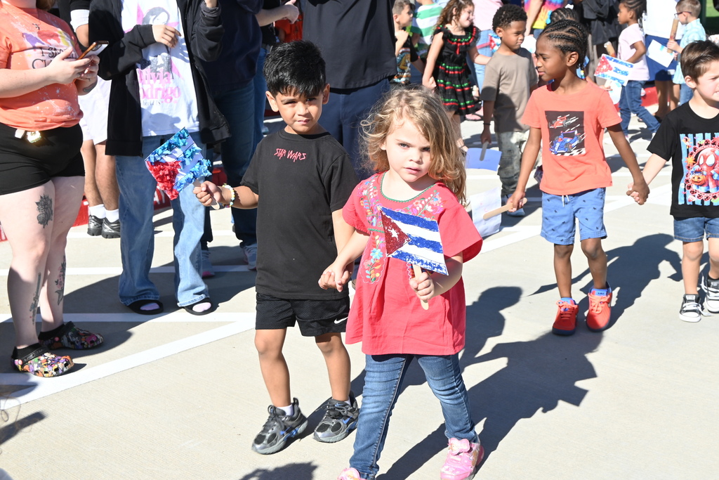 Students holding hands while walking in the parade and holding hadmade hand-held flags from Cuba