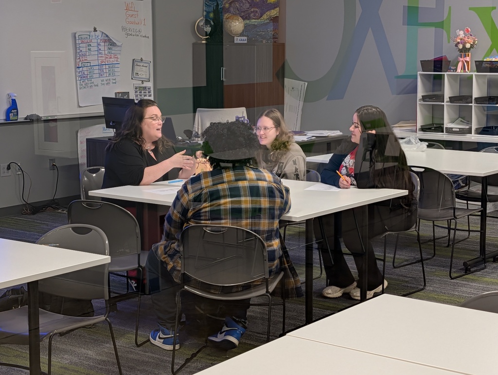 Photo of a teacher helping a group of students.